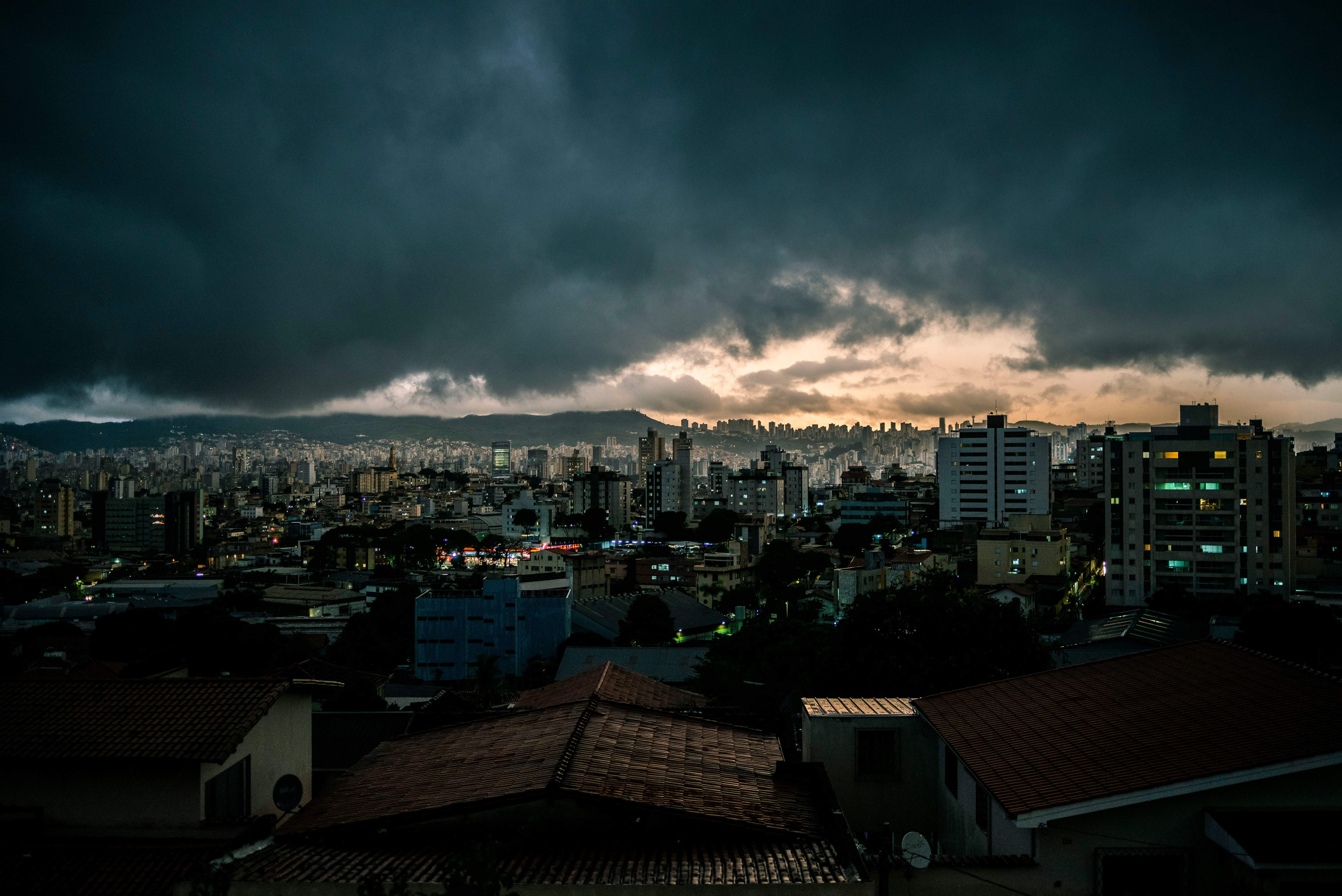 city with high rise buildings under gray clouds during night time